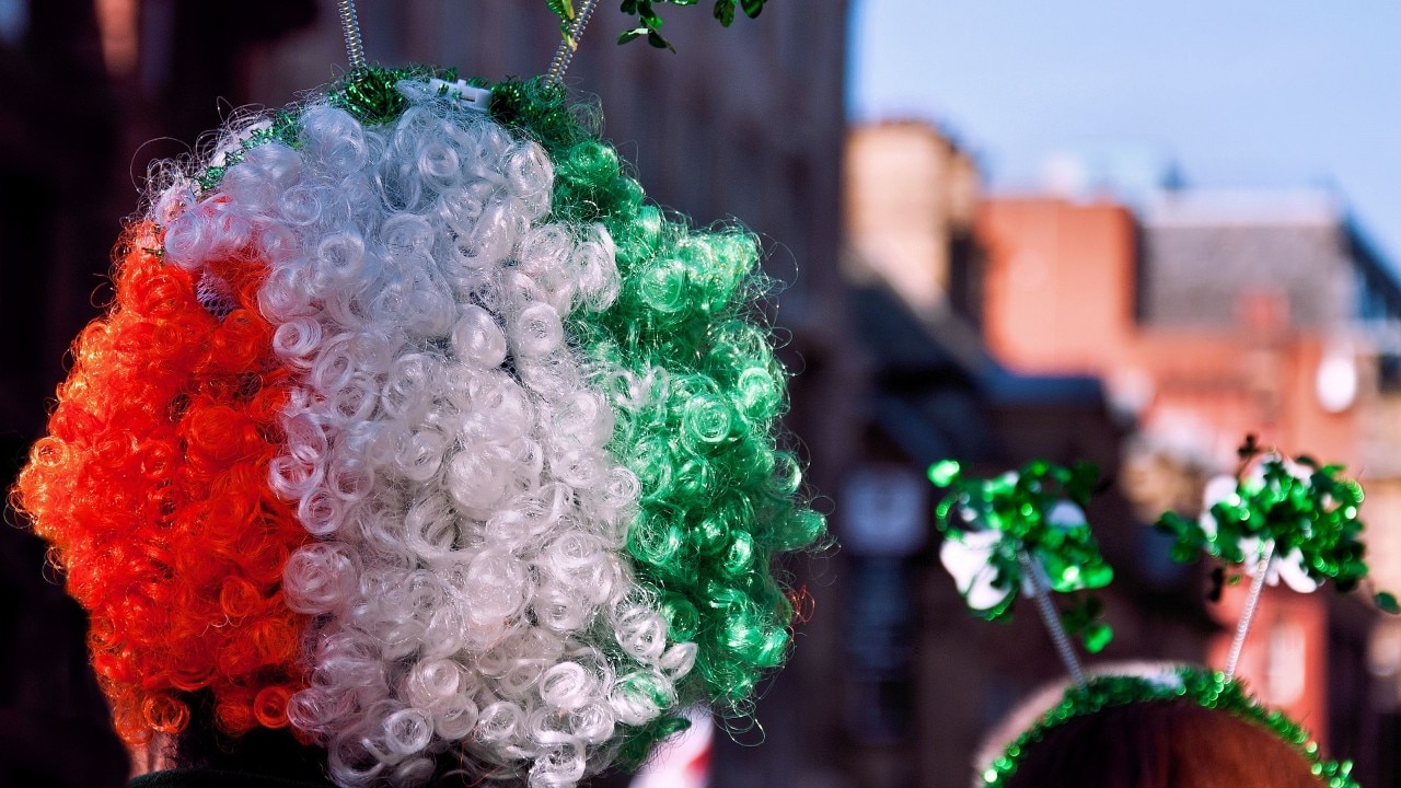 Person in crowd wearing colorful Ireland flag wig at St Patricks Day Parade